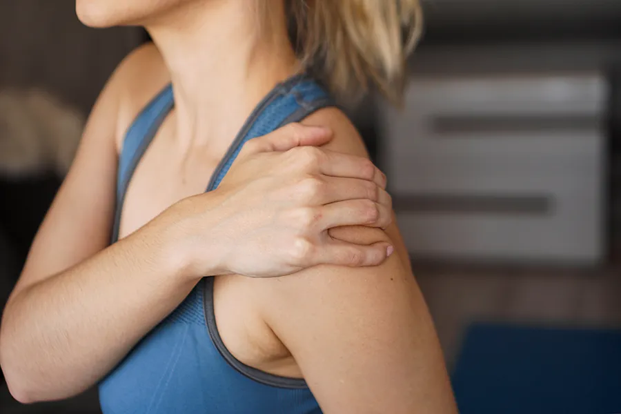 A woman massages her sore shoulder. Get chronic inflammation treatment from Morgan Burns, APRN in Central Florida.