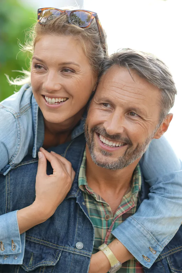 A couple in denim jackets embrace playfully outdoors. Get hypogonadism treatment from Morgan Burns, APRN in Central Florida.