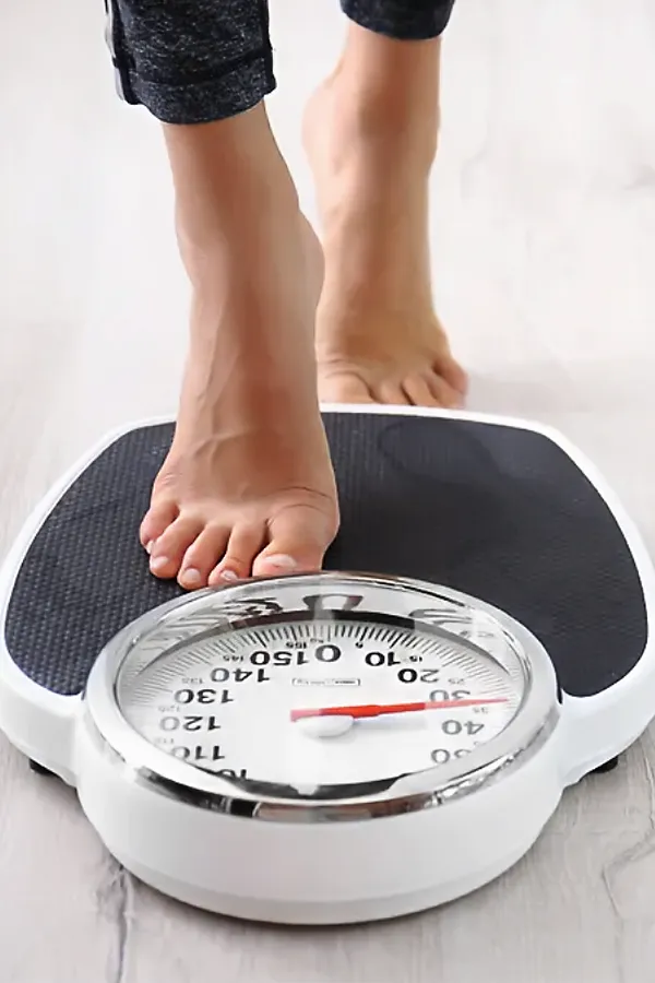 A woman steps onto a scale. Get Metabolilc and Weight Optimization Peptides treatment from Morgan Burns, APRN in Central Florida.