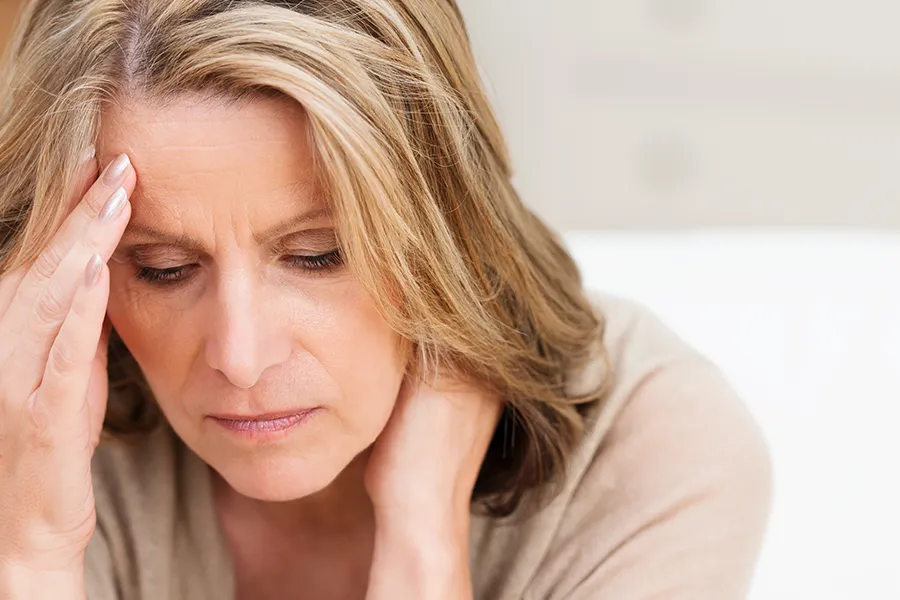 A woman rubs her forehead with worry. Schedule treatment for mood imbalances from Morgan Burns, APRN in Central Florida.