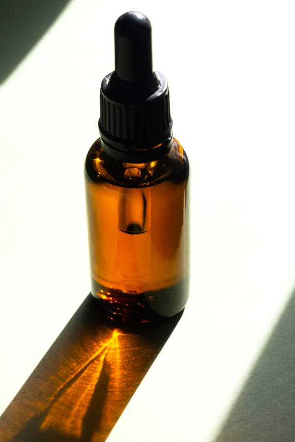 A brown dropper bottle on a table lit by sunlight, representing performance enhancing peptide treatment from Morgan Burns, APRN in Central Florida.
