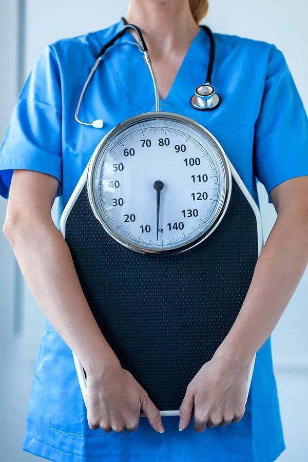 A clinician holds a scale. Sign up for the weight management program with Morgan Burns, APRN in Central Florida.
