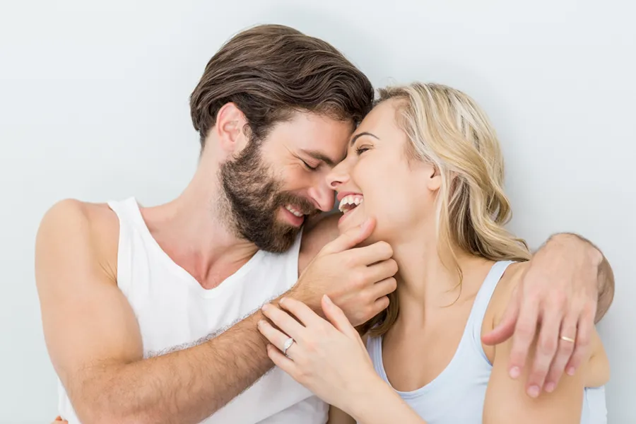 A happy couple embrace in bed. Get Birth Control treatment from Christine Collins, MD in Westside/Beverly Hills.