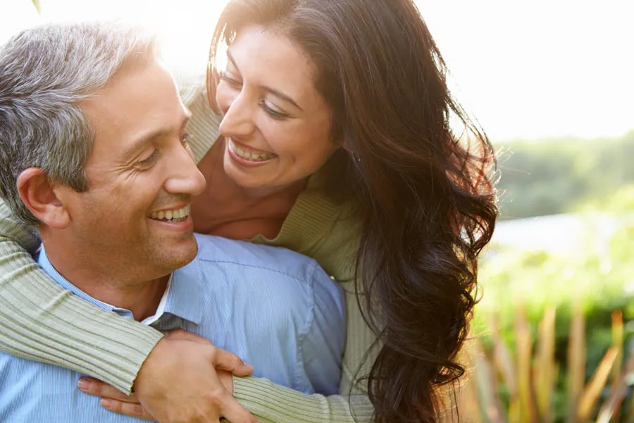 A latin couple embrace in a sunny meadow. Get longevity medicine treatment from Christine Collins, MD in Westside/Beverly Hills.