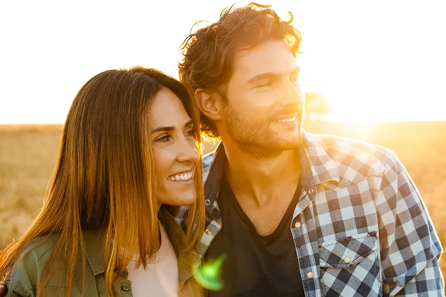 A middle-aged couple stand in a field at sunset. Schedule MIC Vitamin Injection treatment from Christine Collins, MD in Westside/Beverly Hills.