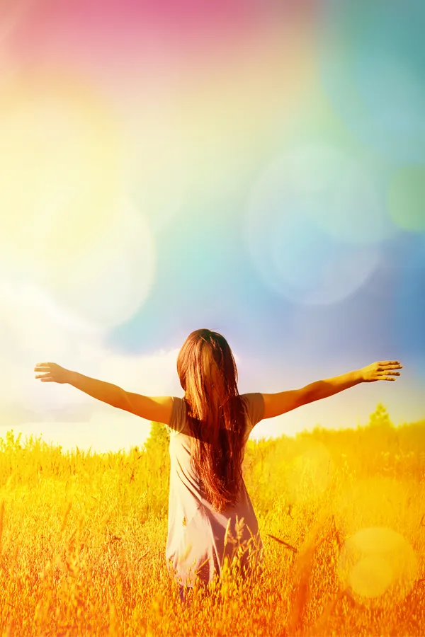 A woman stands in a field with outstretched arms. Get MIC Vitamin Injection treatment from Christine Collins, MD in Westside/Beverly Hills.