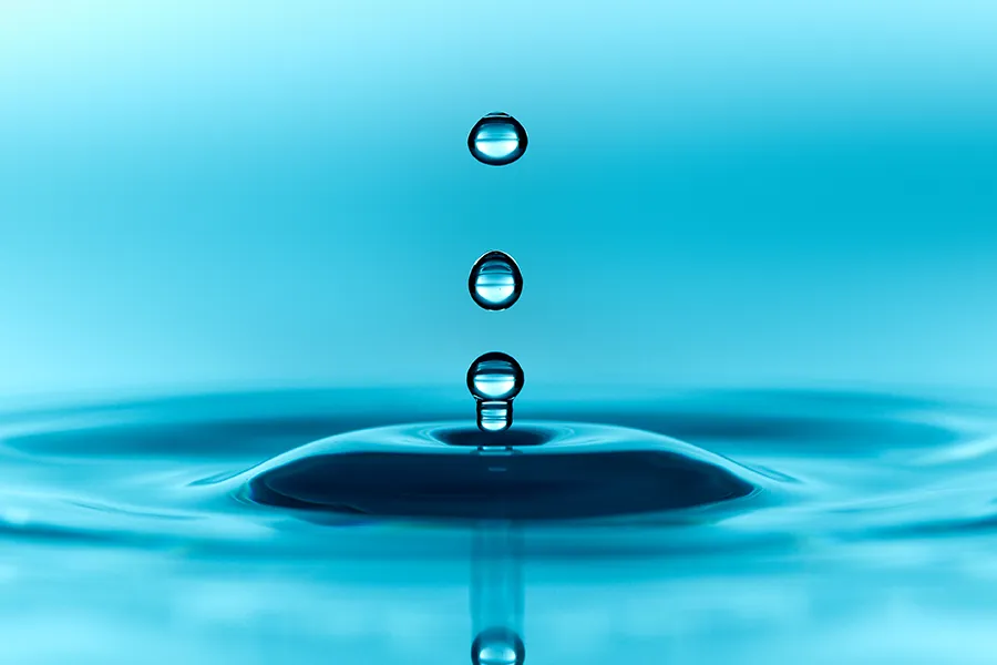 Close-up of water dripping into a blue pool making ripples. Schedule methylene blue IV therapy from Christine Collins, MD in Westside/Beverly Hills.