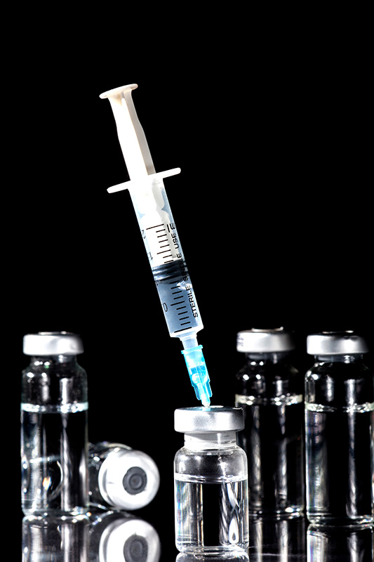 Close-up of a syringe piercing a vial of fluid. Get NAD+ injections from Christine Collins, MD in Westside/Beverly Hills.