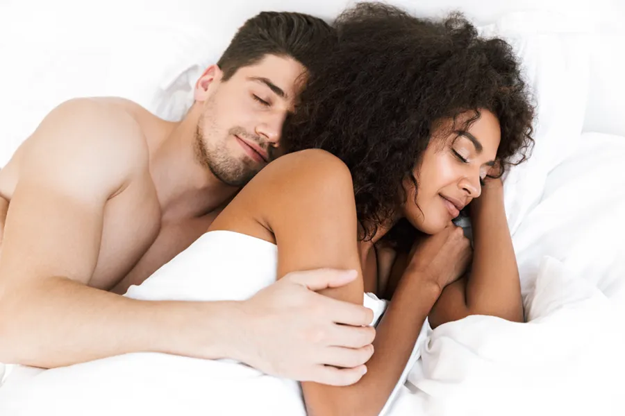 A white man and black woman in bed. Get STD testing from Christine Collins, MD in Westside/Beverly Hills.