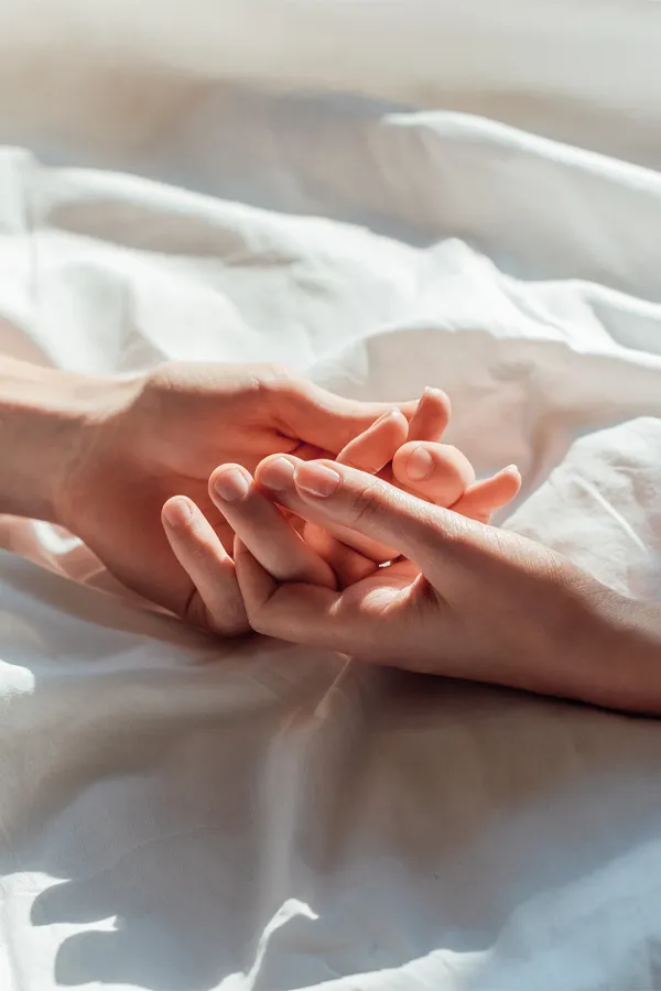 Hands clasping on top of sheets. Get STD testing from Christine Collins, MD in Westside/Beverly Hills.