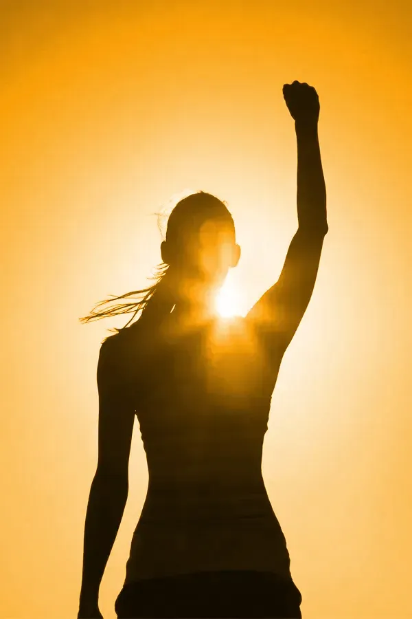 A woman raises her hand in triumph in the sunlight. Get Vitamin D3 Injections from Christine Collins, MD in Westside/Beverly Hills.