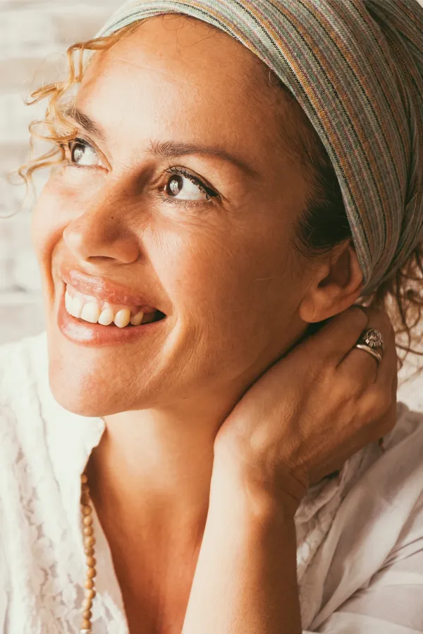 A woman wrapped in towels enjoying a red-lit sauna. Get infrared sauna treatment from Christine Collins, MD in Westside/Beverly Hills.