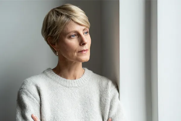 A blond, middle-aged woman looks out the window with a tired expression. Get chronic fatigue treatment from Frank Lanzisera, D.C. in Tampa Bay Metro.