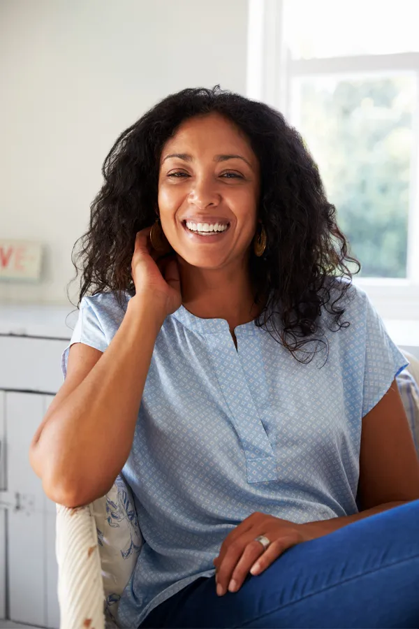 A healthy, happy middle-aged black woman sitting in a sunlit room. Get IV Therapy for digestive health from Frank Lanzisera, D.C. in Tampa Bay Metro.