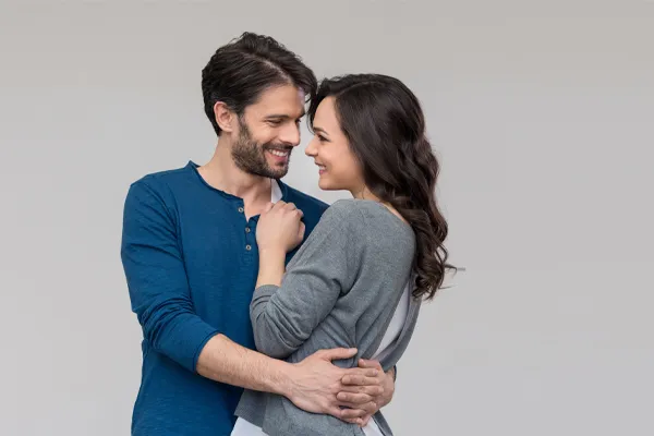A man in a blue shirt embracing a woman in a gray shirt smiles due to his successful erectile dysfunction care from Frank Lanzisera, D.C. in Tampa Bay Metro.