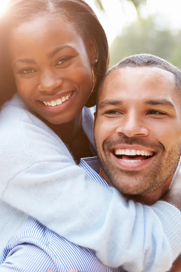 A woman riding on a man's back, both smiling due to help with erectile dysfunction from Frank Lanzisera, D.C. in Tampa Bay Metro.