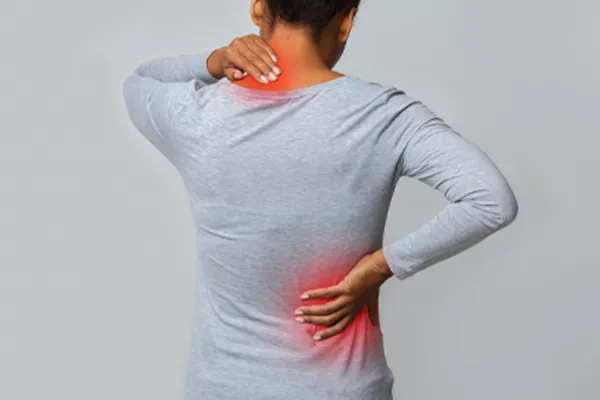An image from behind of a woman suffering from Fibromyalgia holding her hands on her neck and lower back. Get fibromyalgia care from Frank Lanzisera, D.C. in Tampa Bay Metro.