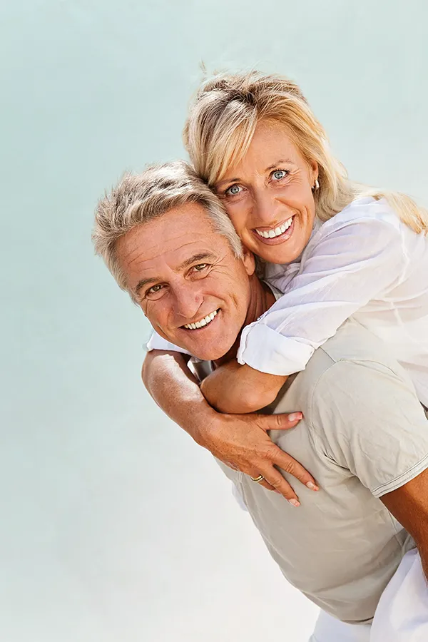 A happy mature couple having fun - the husband is carrying his wife on his back. Get treatment for food allergies from Frank Lanzisera, D.C. in Tampa Bay Metro.