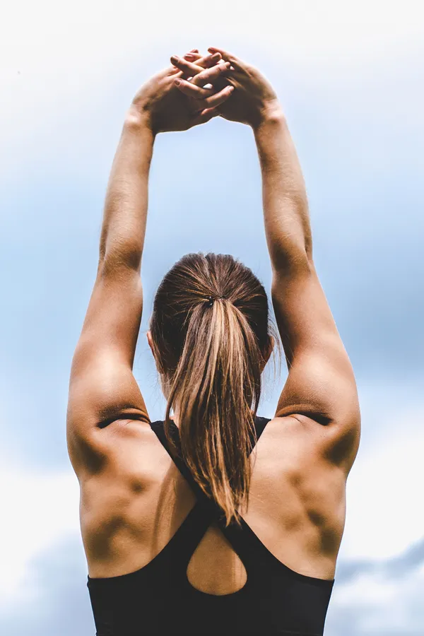 A toned woman stretches her arms before a workout. Get Get Up & Go IV therapy from Frank Lanzisera, D.C. in Tampa Bay Metro.