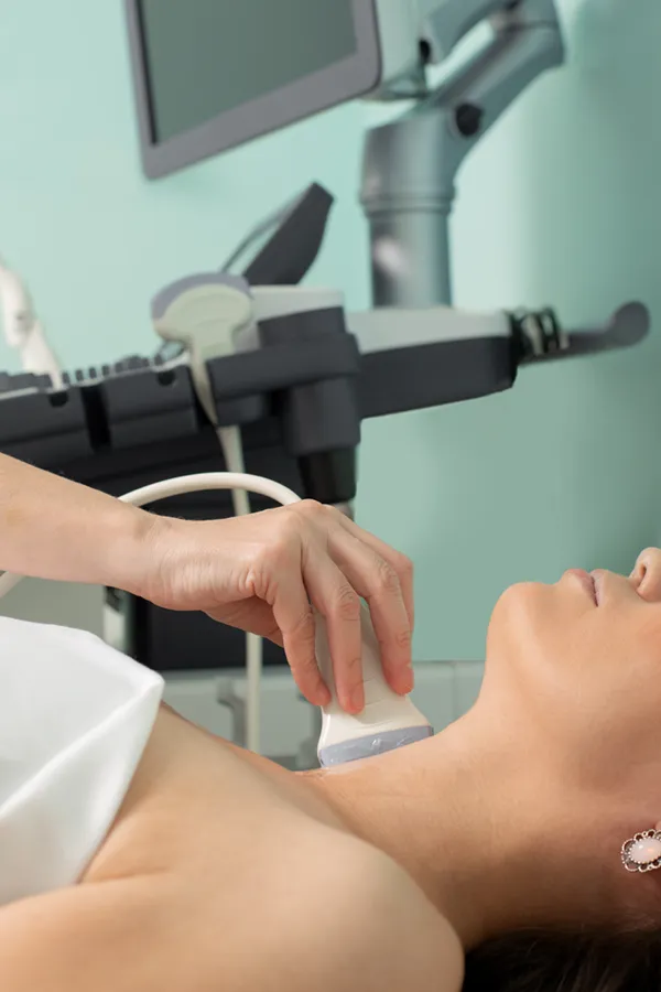 A woman gets a thyroid scan from a doctor in a clinic. Get help with Hashimoto's Thyroiditis from Frank Lanzisera, D.C. in Tampa Bay Metro.
