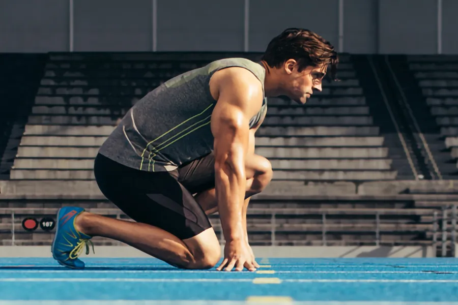 A white man kneels at the starting line on a track, determined to do his best. Get treatment for lean muscle loss and recovery from Frank Lanzisera, D.C. in Tampa Bay Metro.
