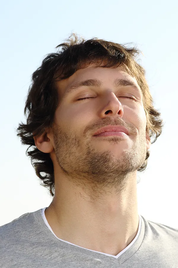 A brown-haired man closes his eyes and breathes in fresh air with his face turned up to the sky. Get treatment for Lupus from Frank Lanzisera, D.C. in Tampa Bay Metro.