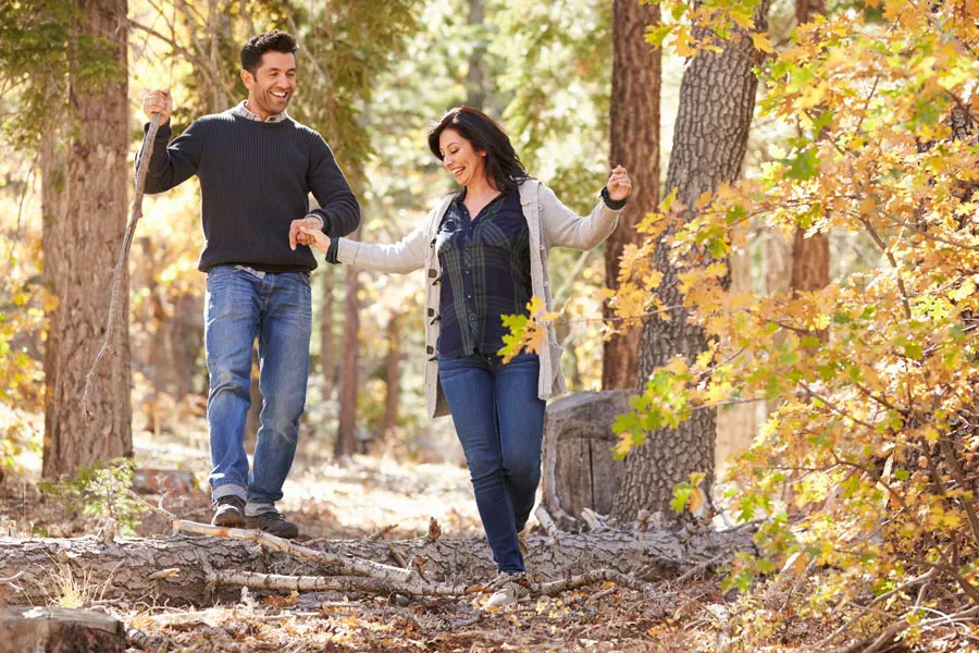 A couple happily hiking in the forest in fall. Get treatment for Lyme Disease from Frank Lanzisera, D.C. in Tampa Bay Metro.