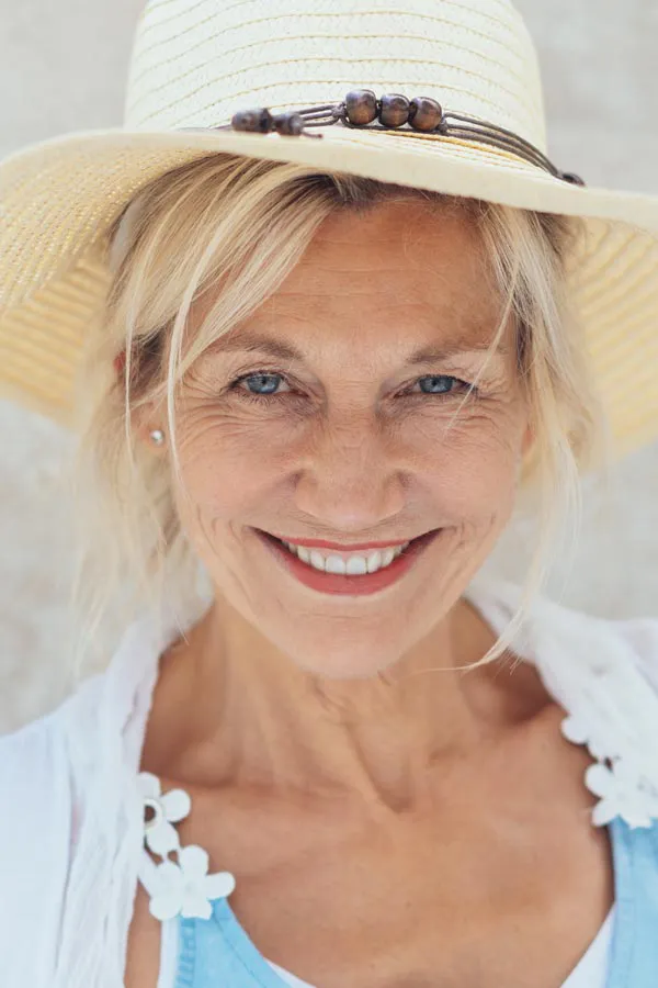 A woman in a mask sits outside with her hand on her forehead in pain. Get post-covid treatment from Frank Lanzisera, D.C. in Tampa Bay Metro.