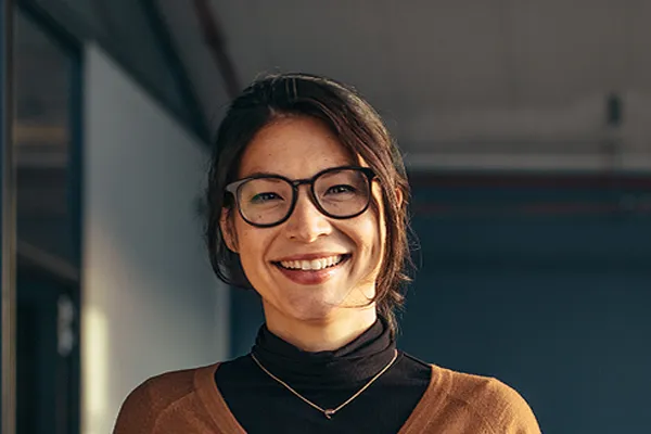 A brunette woman with glasses smiles in a gray-blue walled office. Get metabolic syndrome from Frank Lanzisera, D.C. in Tampa Bay Metro.