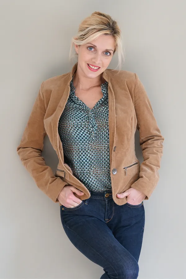 A smiling blonde woman in a tan leather jacket leans against a gray wall. Schedule metabolic syndrome from Frank Lanzisera, D.C. in Tampa Bay Metro.