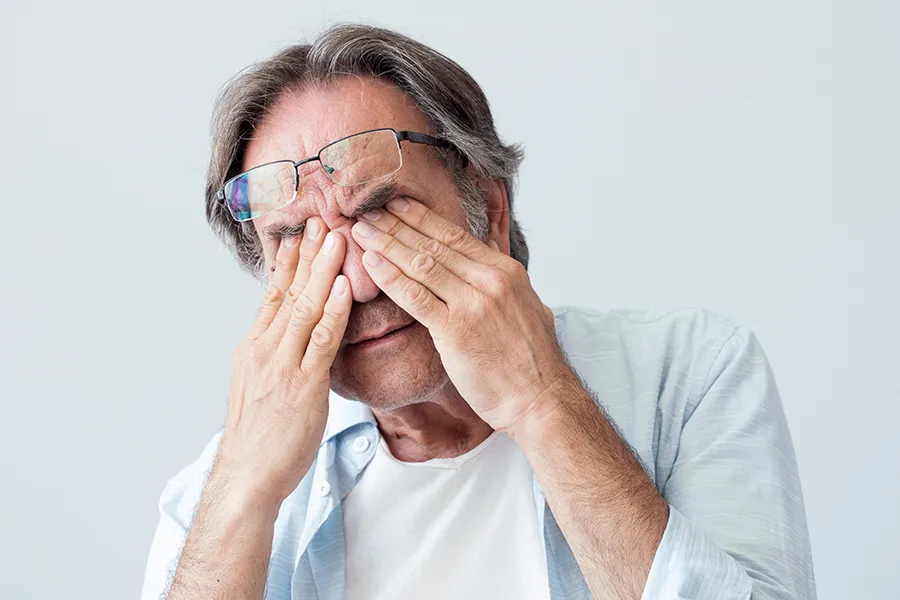 Get migraine relief with Frank Lanzisera, D.C.'s functional medicine for migraines treatment in Tampa Bay Metro, represented by an older man rubbing his eyes due to head pain.