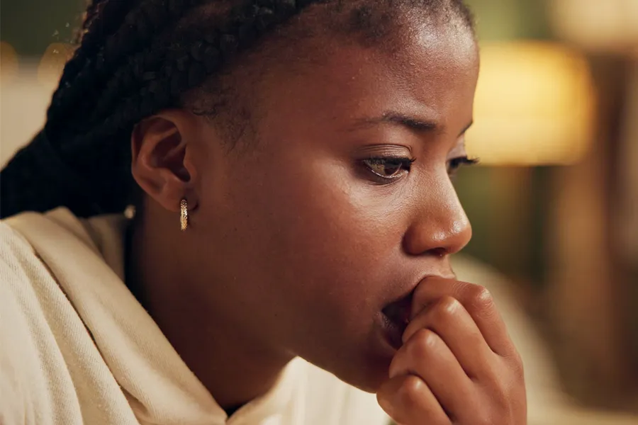 A black woman feeling stress bites her nails and looks withdrawn. Get treatment for mood imbalances and stress from Frank Lanzisera, D.C. in Tampa Bay Metro.