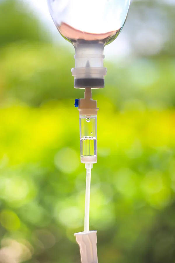 Close-up of an IV drip against a forest background. Get the Myers Cocktail IV treatment from Frank Lanzisera, D.C. in Tampa Bay Metro.