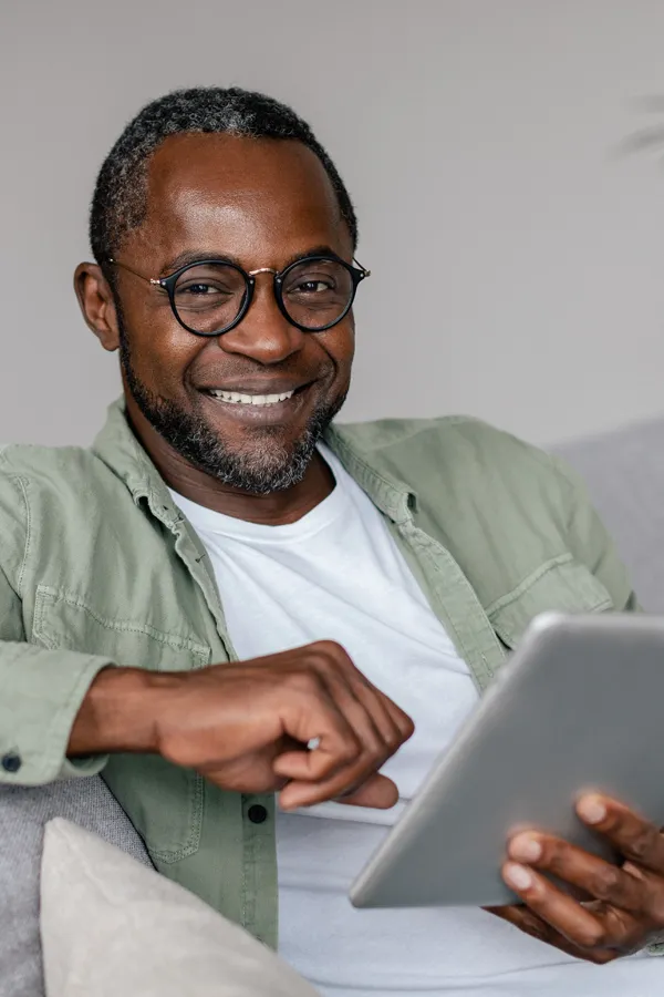 A smiling Black man working on a tablet. Get neurofeedback therapy from Frank Lanzisera, D.C. in Tampa Bay Metro.