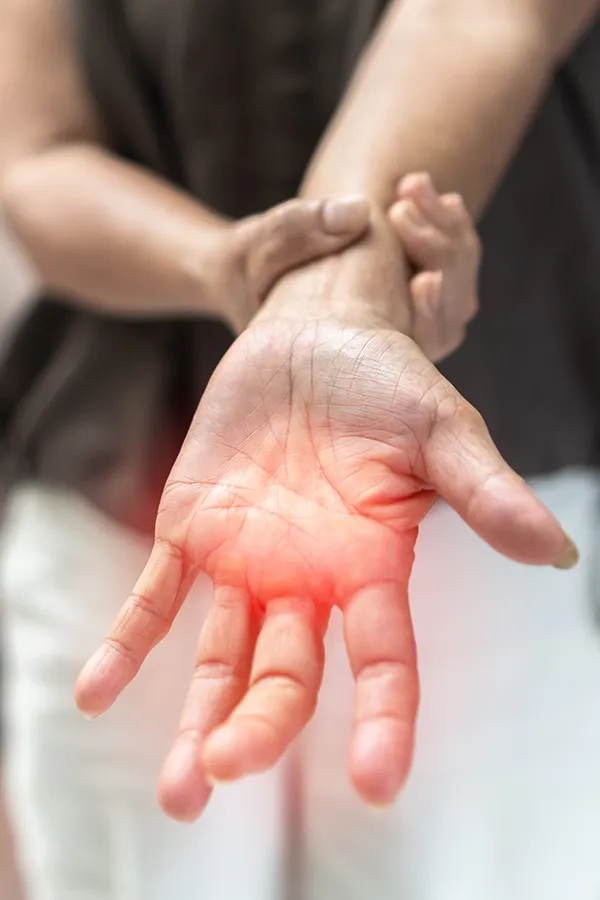 A woman holds her wrist with nerve pain. Get Neuropathy and Nerve Pain Treatment from Frank Lanzisera, D.C. in Tampa Bay Metro.