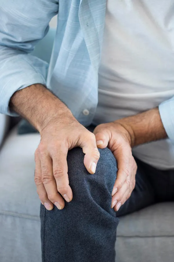 A close-up of a man holding his knee while experiencing pain from osteoporosis. Get osteoporosis treatment from Frank Lanzisera, D.C. in Tampa Bay Metro.