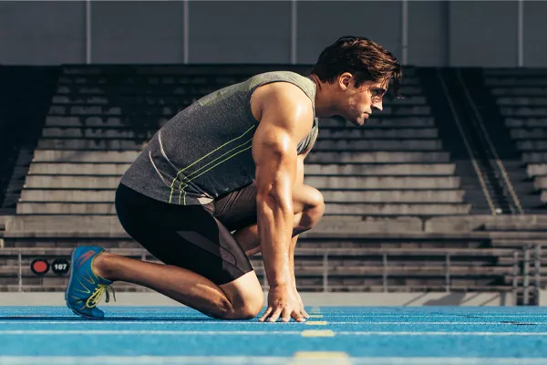 A strong man gets ready to race at the starting line of a track. Schedule IV Therapy for performance recovery relief from Frank Lanzisera, D.C. in Tampa Bay Metro.