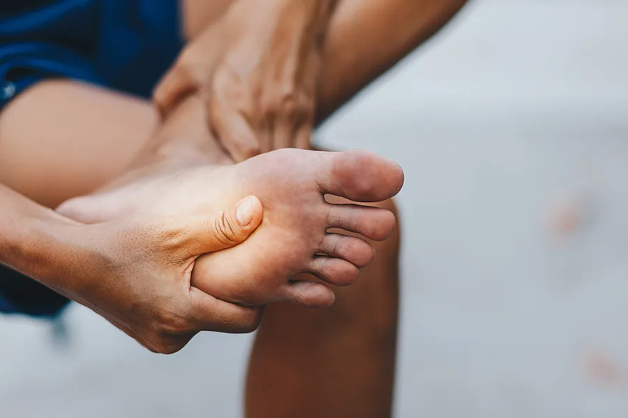 A man holds is foot which shows an inflamed area. Schedule treatment for peripheral neuropathy from Frank Lanzisera, D.C. in Tampa Bay Metro.