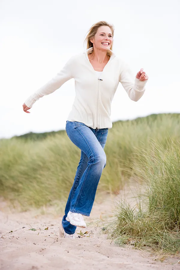 A middle-aged woman runs through a meadow. Get treatment for peripheral neuropathy from Frank Lanzisera, D.C. in Tampa Bay Metro.