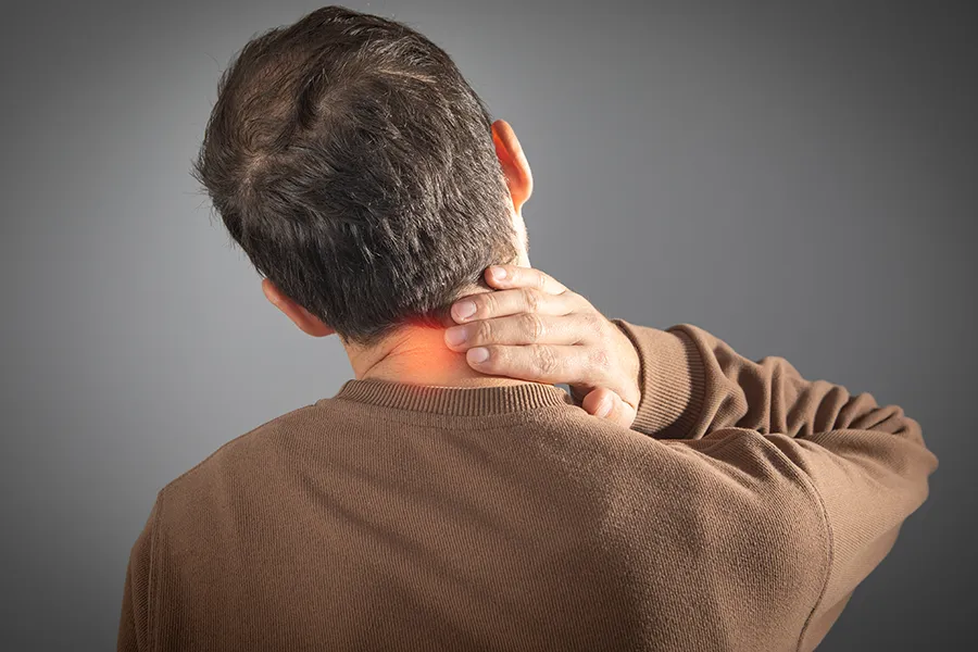 A man rubs his neck in pain. Schedule Regenerative Medicine for Neck Pain from Frank Lanzisera, D.C. in Tampa Bay Metro.