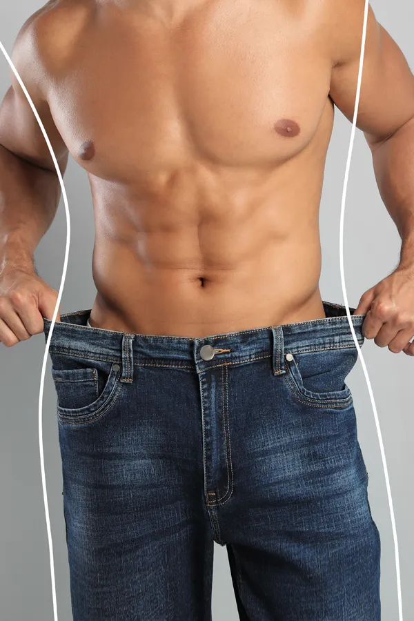 A strong shirtless man in jeans holds the waistlines of his too-big jeans to show the success of semaglutide weight loss from Frank Lanzisera, D.C. in Tampa Bay Metro.
