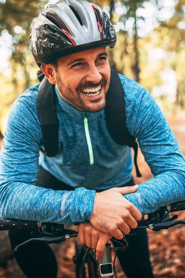 A middle-aged man on a trail in cycling clothes is smiling and leaning on his bike's handlebars. Get testosterone for Low T from Frank Lanzisera, D.C. in Tampa Bay Metro.