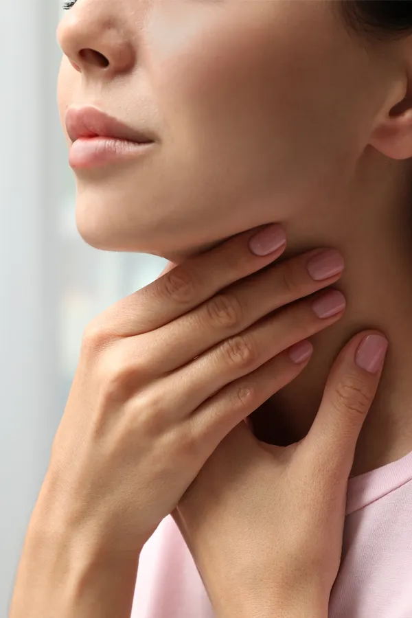 A woman holds her throat in pain. Get treatment for thyroid symptoms from Frank Lanzisera, D.C. in Tampa Bay Metro.
