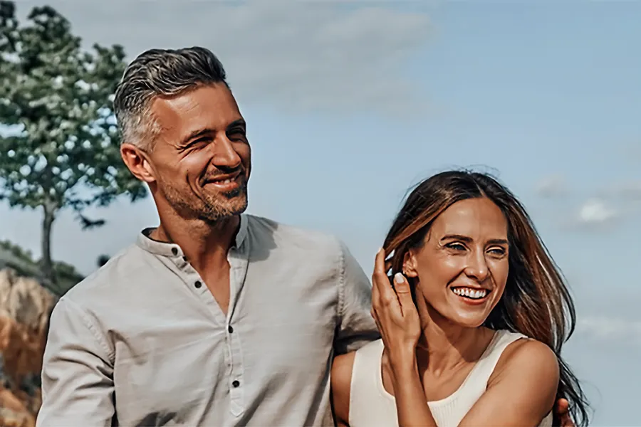 A vibrant middle-aged couple walk on the beach. Schedule Timeless IV therapy from Frank Lanzisera, D.C. in Tampa Bay Metro.