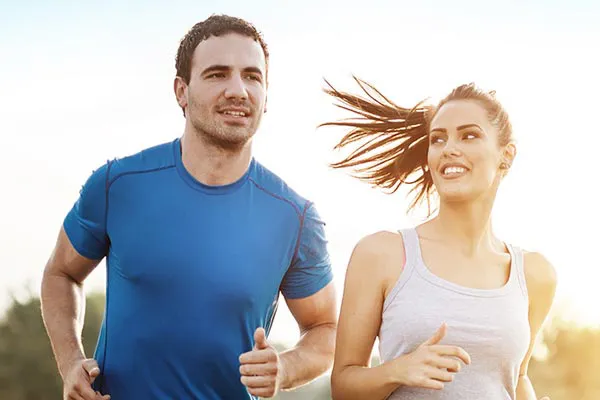 A couple happily jogging in the sunlight after receiving effective weight loss resistance care from Frank Lanzisera, D.C. in Tampa Bay Metro.
